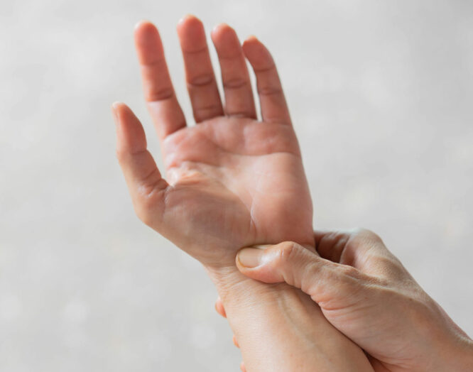 Das Bild zeigt zwei Hände, eine zeigt mit der Handfläche nach oben, die andere fühlt mit dem Daumen das Handgelenk.