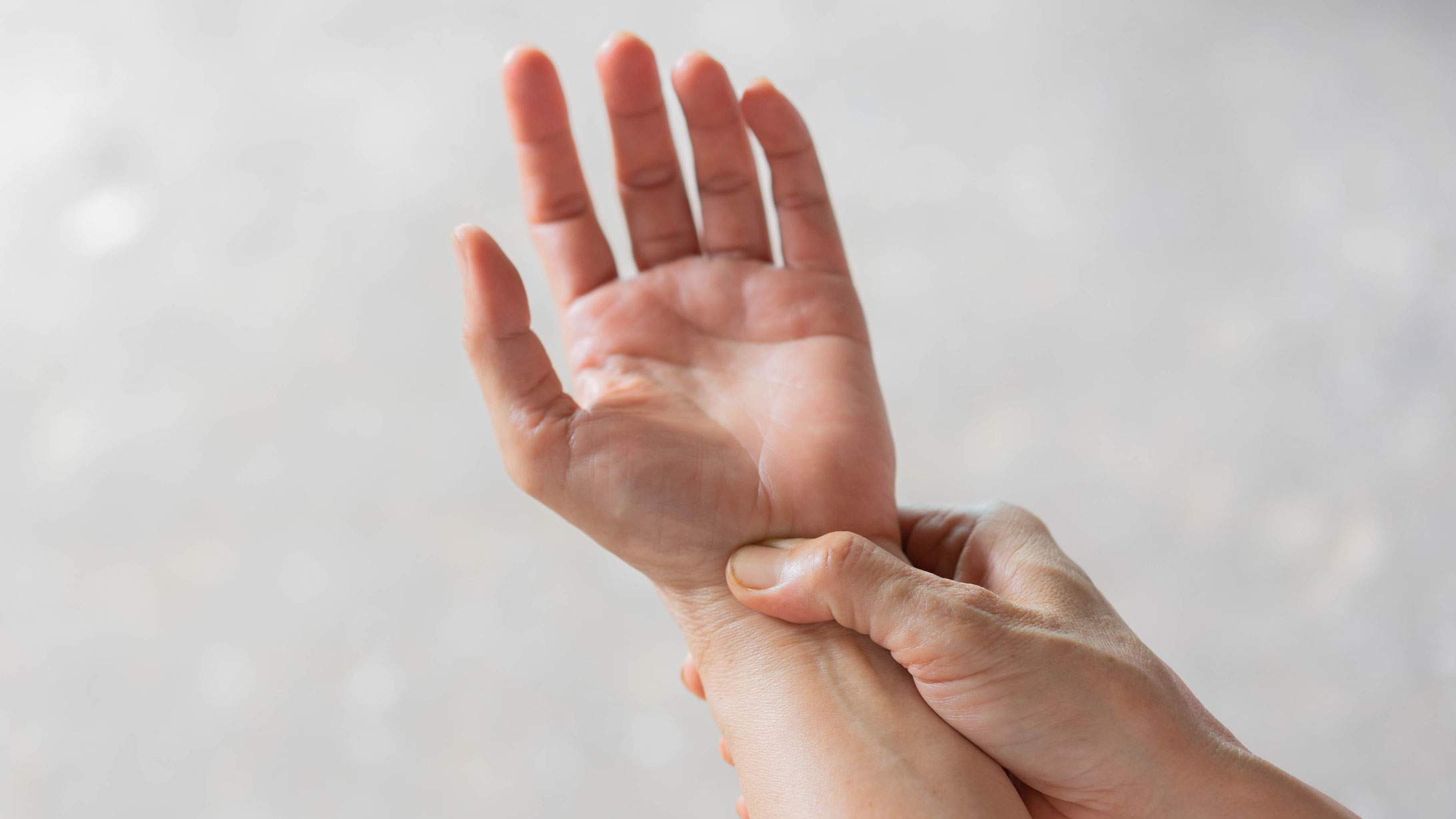 Das Bild zeigt zwei Hände, eine zeigt mit der Handfläche nach oben, die andere fühlt mit dem Daumen das Handgelenk.