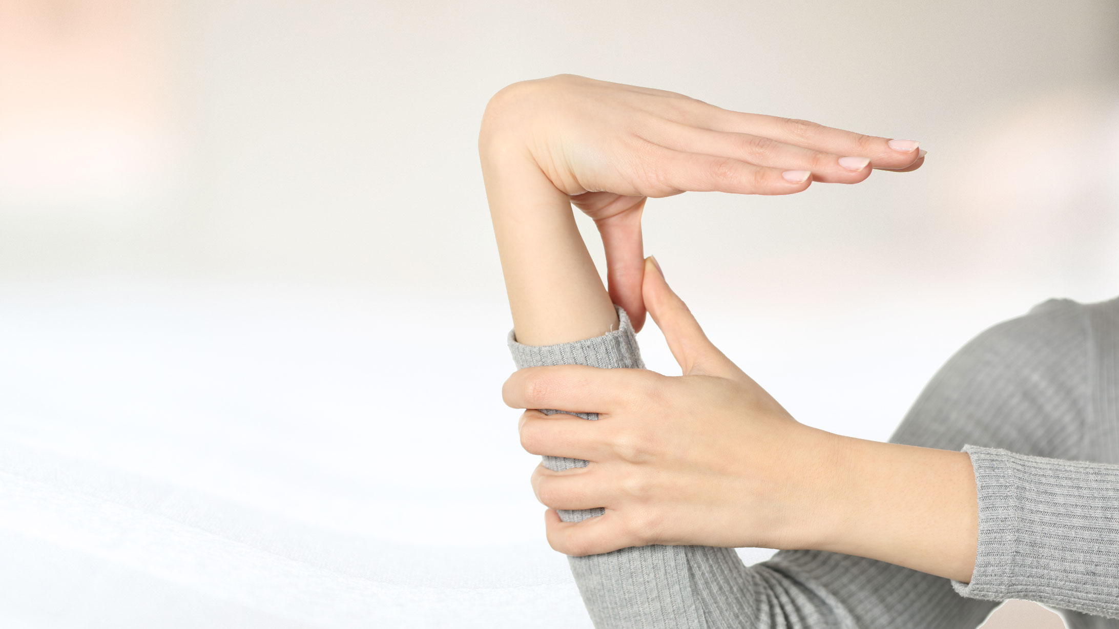 Hyperlaxizität: Eine Frau biegt das Handgelenk und den Daumen stark durch.