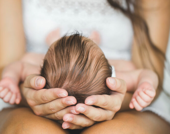 Eine Frau hält den Kopf eines Neugeborenen