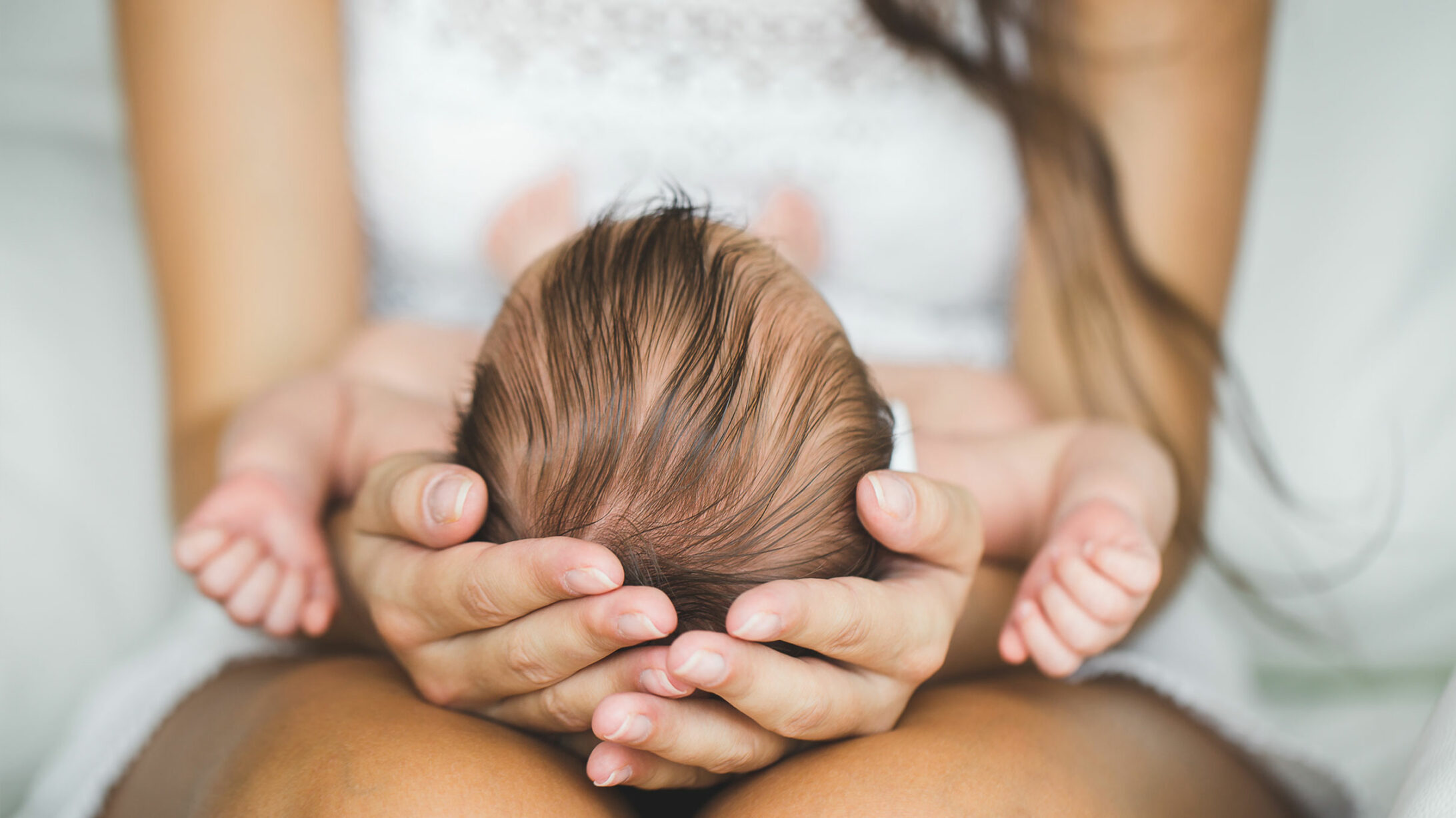 Eine Frau hält den Kopf eines Neugeborenen
