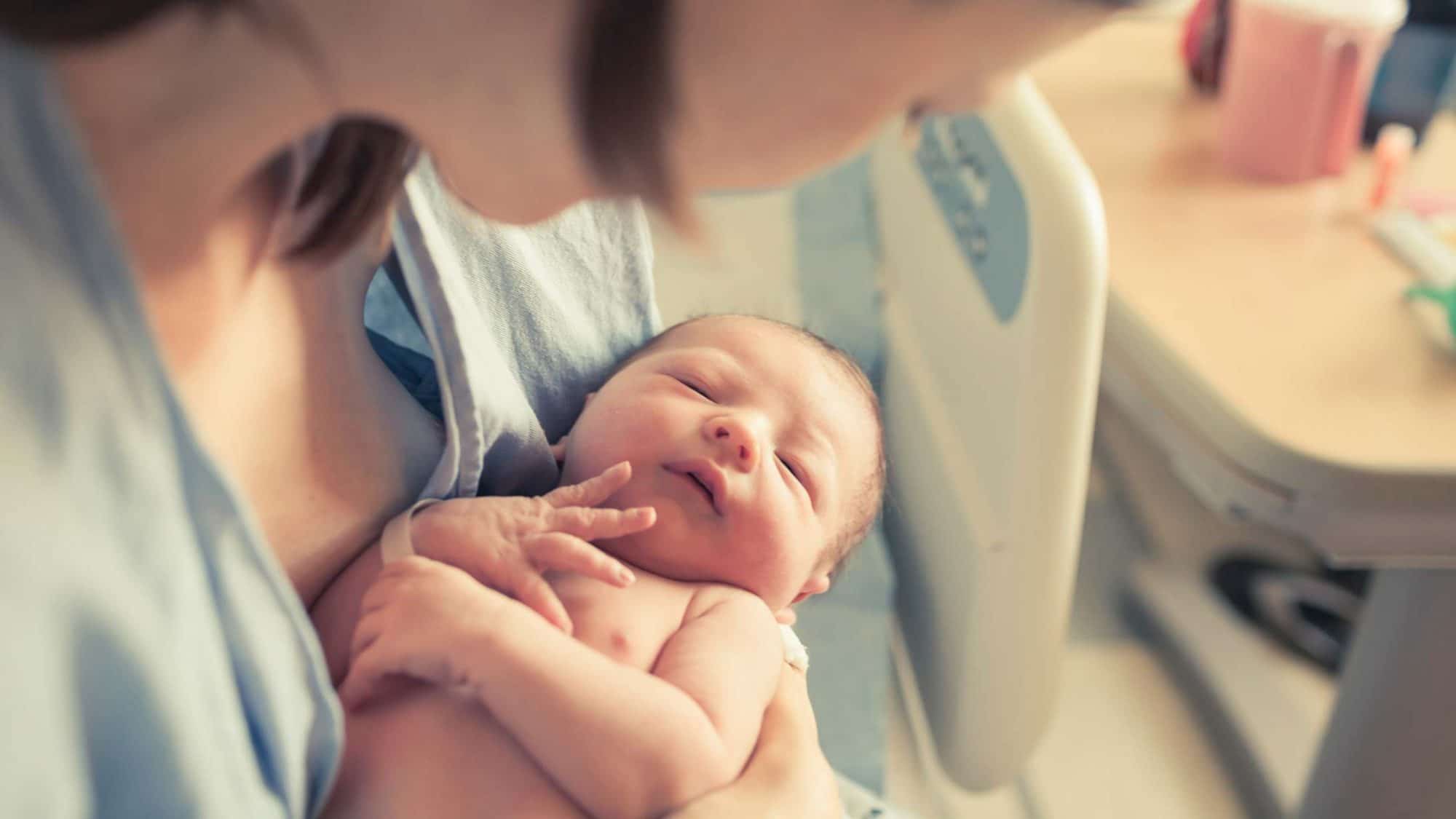 Ein neugeborenes Baby in den Armen seiner Mutter.