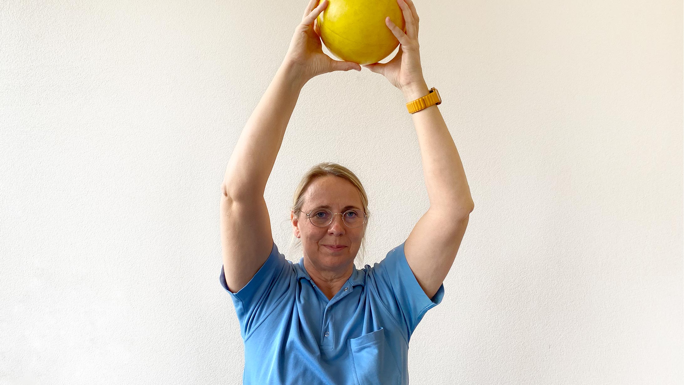 Physiotherapeutin Monika Loebel trainiert mit einem gelben Ball.
