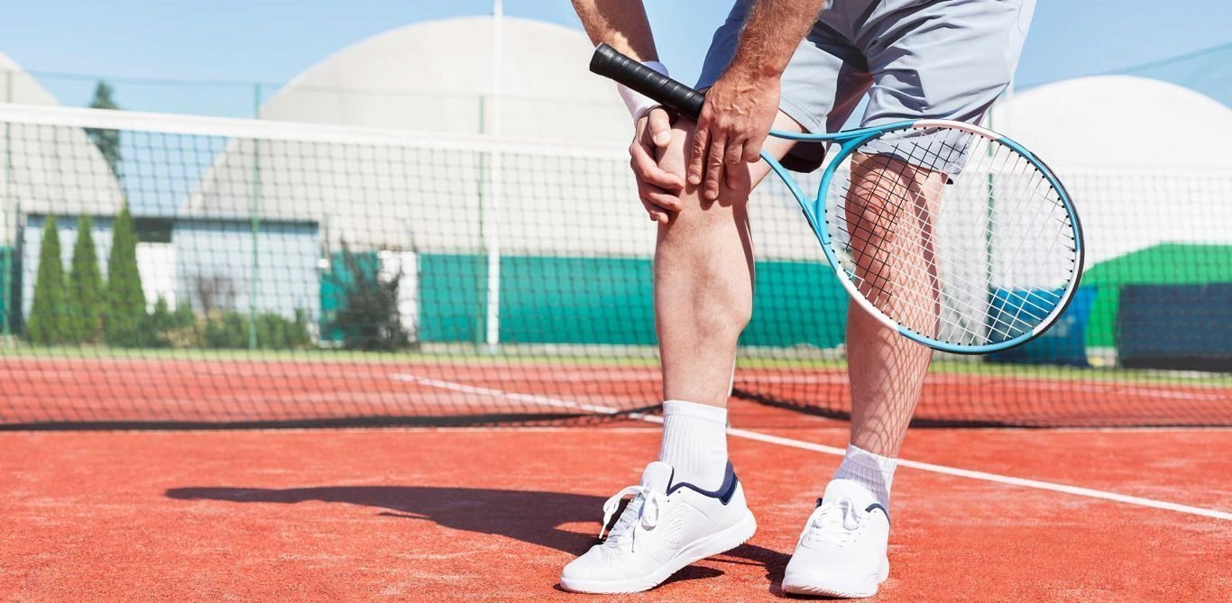 Ein Tennisspieler hält sich das schmerzende Knie.