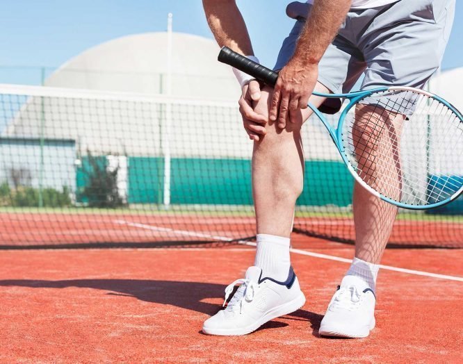 Ein Tennisspieler hält sich das schmerzende Knie.