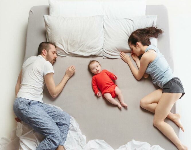 Sex nach Geburt: Ehepaar im Bett mit Baby dazwischen