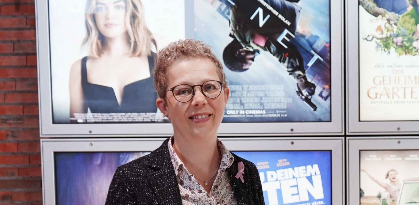 Alexandra Sterk, die an Brustkrebs erkrankte, steht in ihrem Kino vor den Plakaten der aktuellen Filmen.
