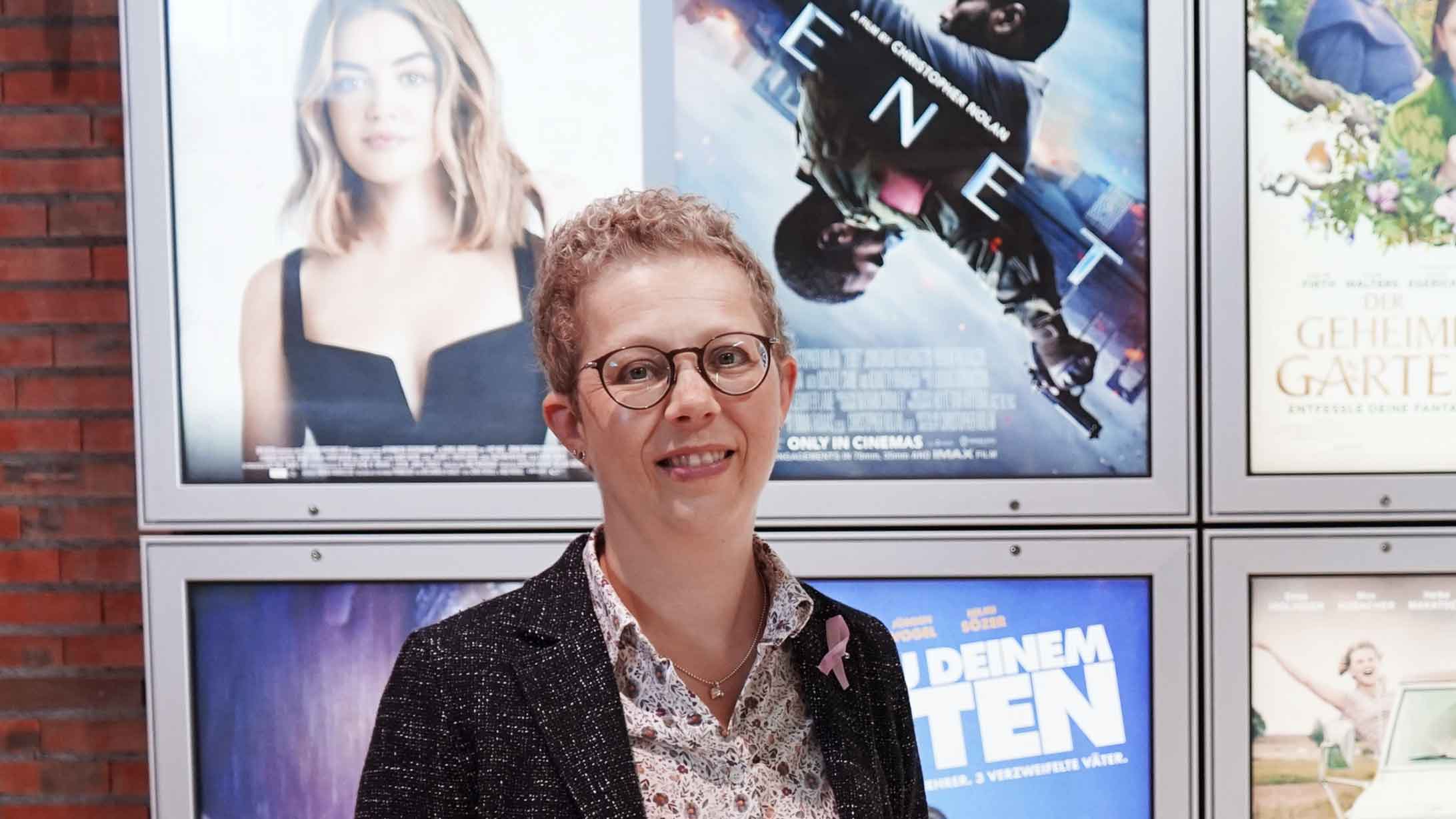 Alexandra Sterk, die an Brustkrebs erkrankte, steht in ihrem Kino vor den Plakaten der aktuellen Filmen.