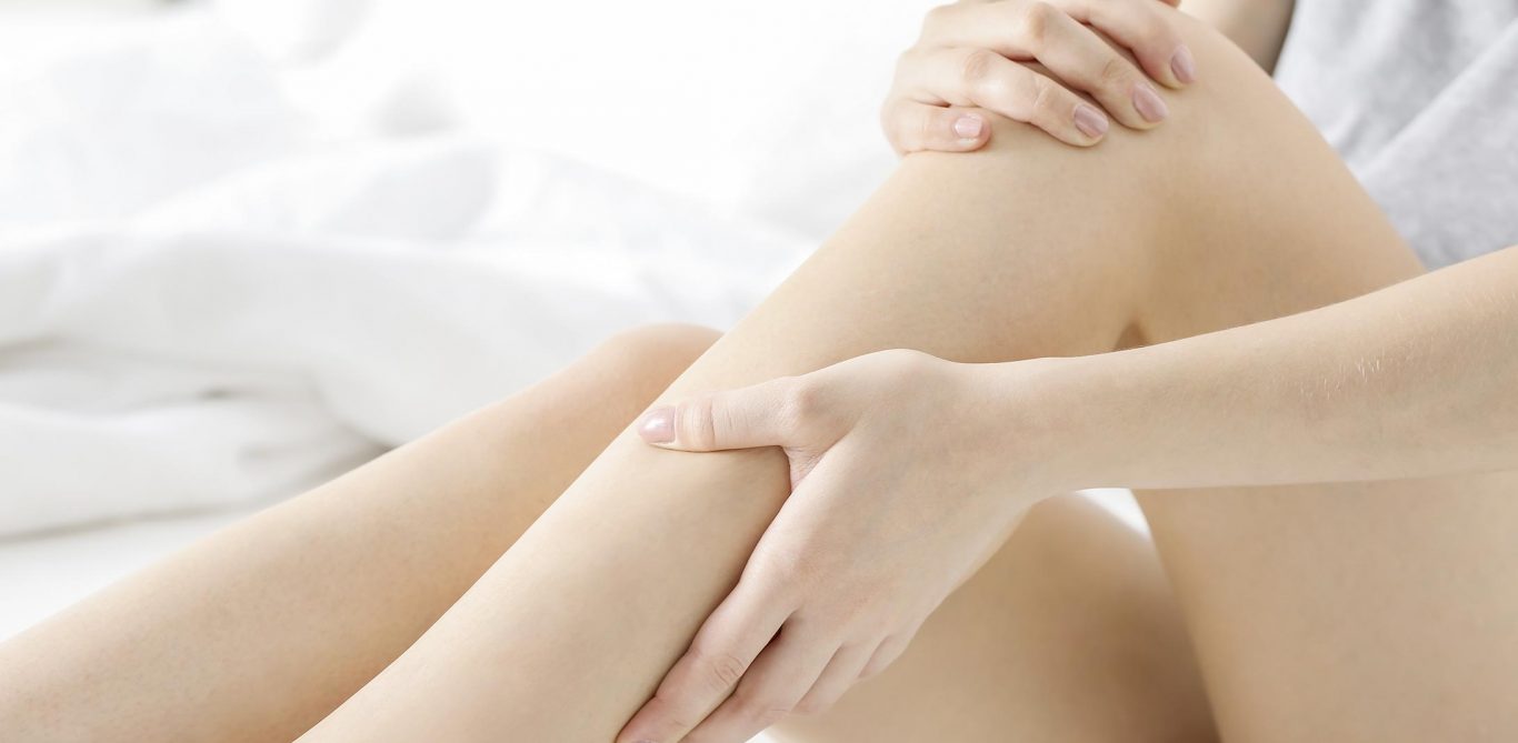 Frau hält sich die Beine. Ein Kribbeln ist typisch für das Restless-Legs-Syndrom.