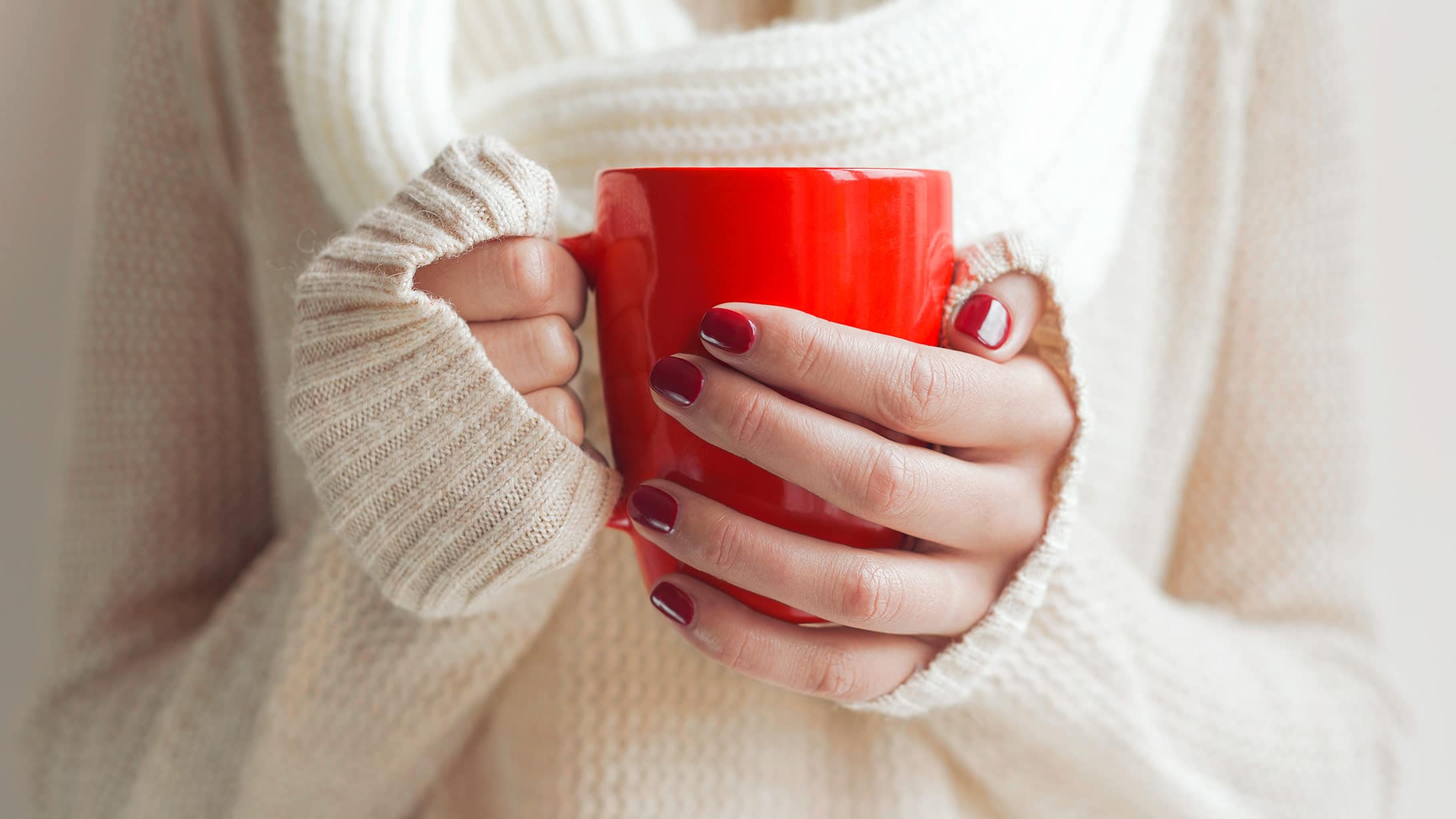 Eine Frau mit kalten Händen hält eine Tasse