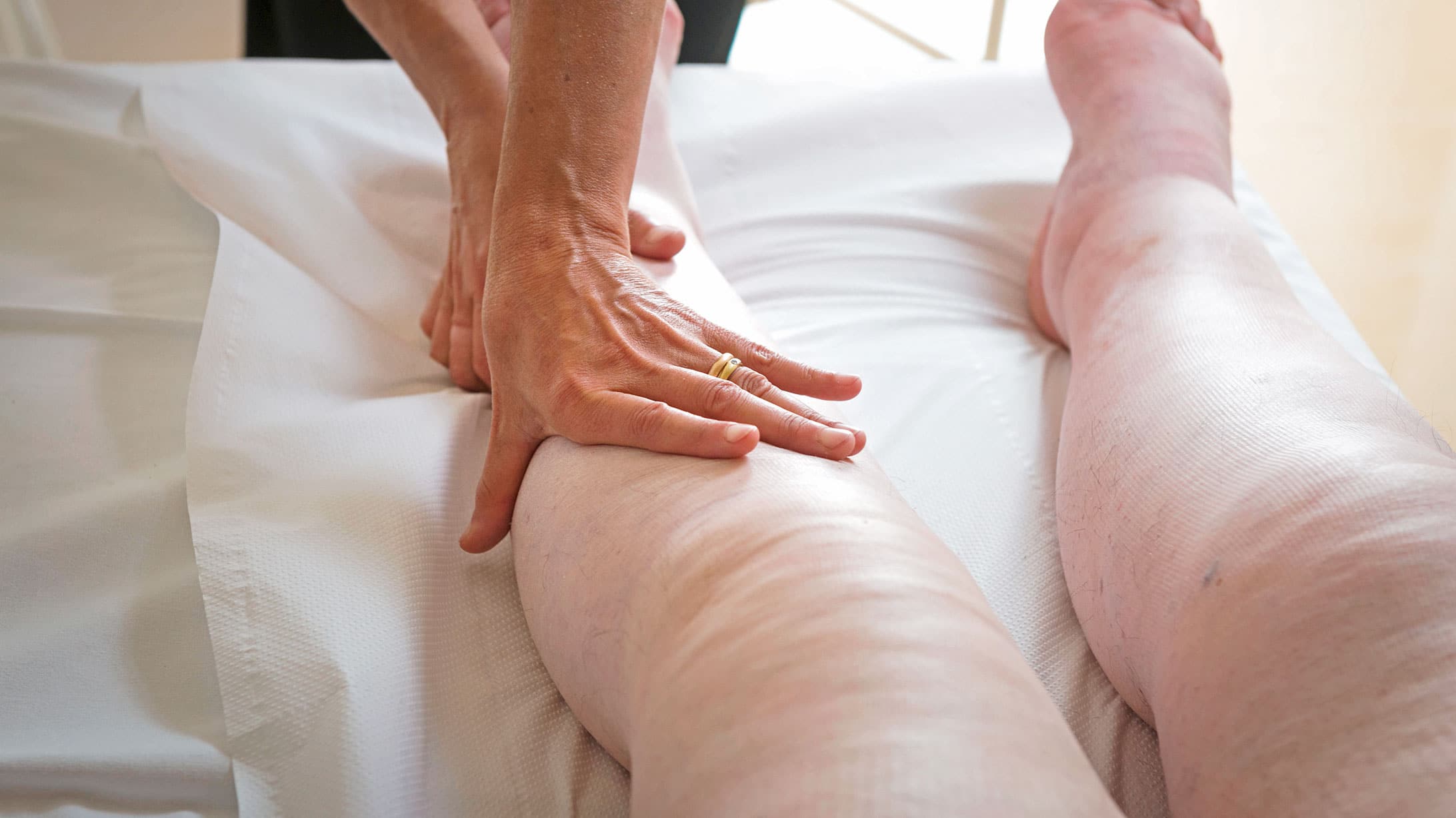 Eine Frau untersucht die Beine einer Patientin mit Lipödem