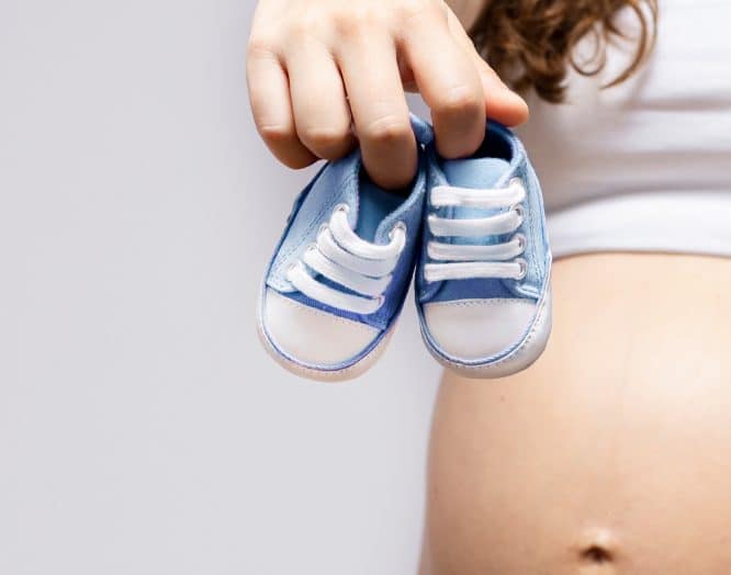 Eine schwangere Frau mit Babyschuhen