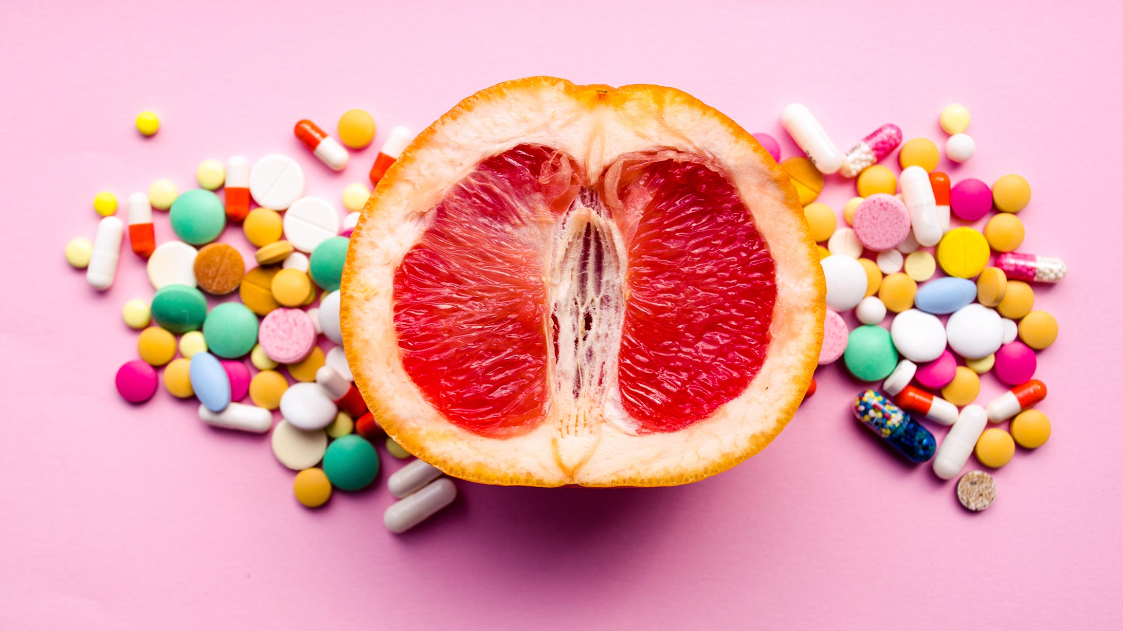 Eine aufgeschnittene Grapefruit mit vielen verschiedenen Tabletten rundherum.