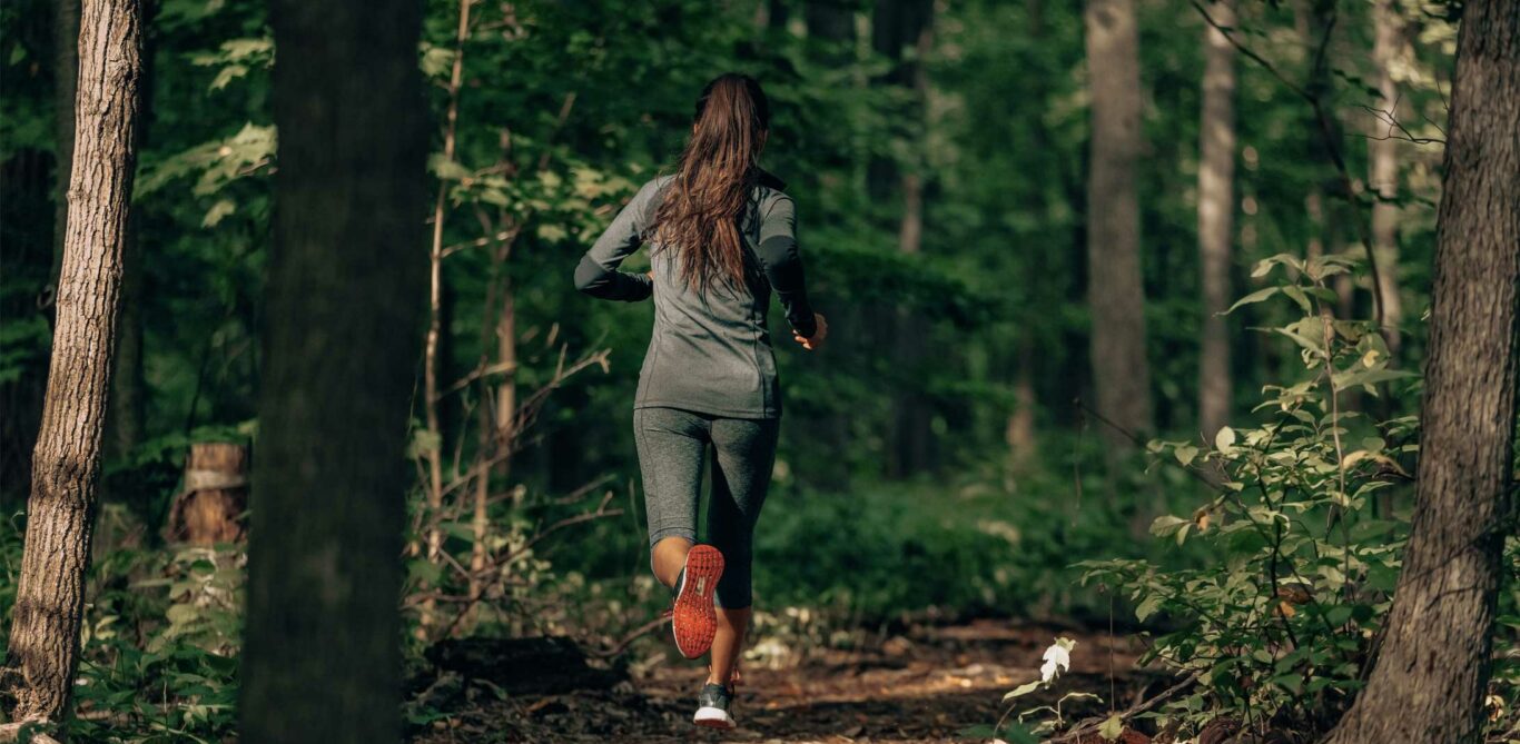 Eine Frau joggt auf einem Waldweg.
