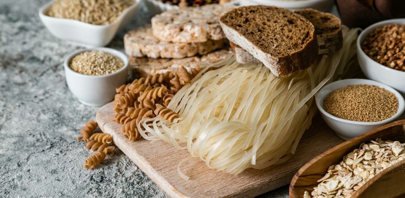 Glutenhaltige Lebensmittel: Brot, Teigwaren, Kerne, Reiswaffeln liegen schön hergerichtet da