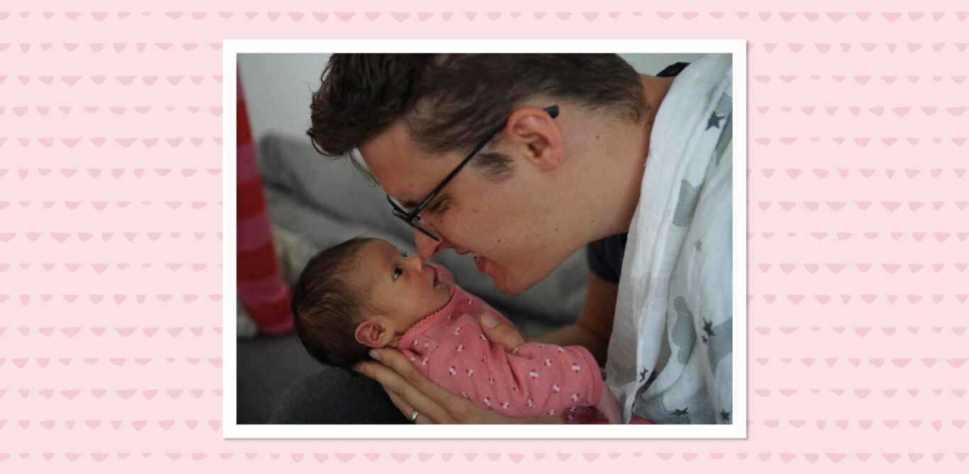 Ein junger Vater hält seine neugeborene Tochter ans Gesicht.