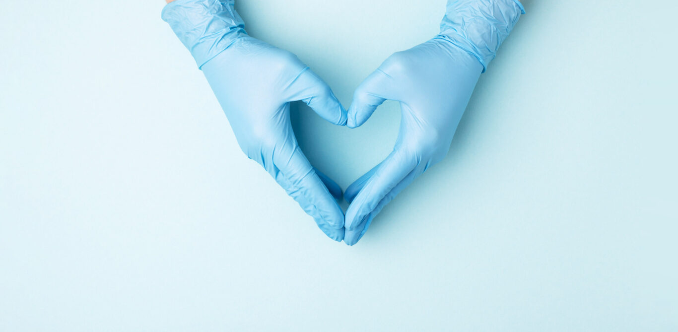 Clinical Nurse: zwei Hände in blauen Plastikhandschuhen formen ein Herz