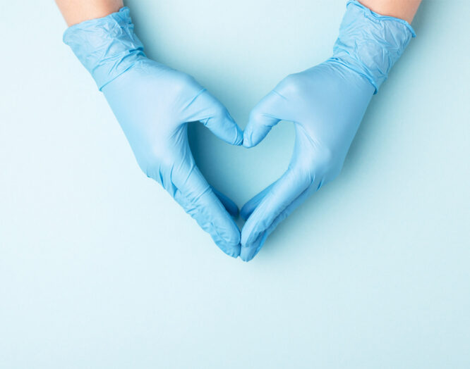 Clinical Nurse: zwei Hände in blauen Plastikhandschuhen formen ein Herz
